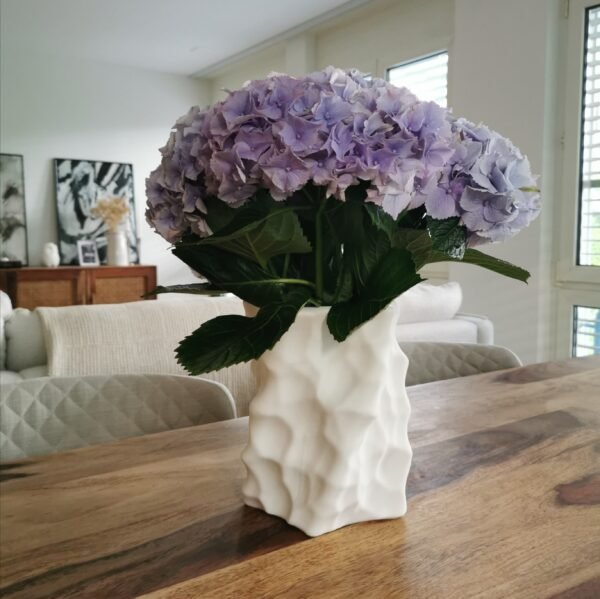 White 3D-printed sculptural vase filled with blooming light purple hydrangeas