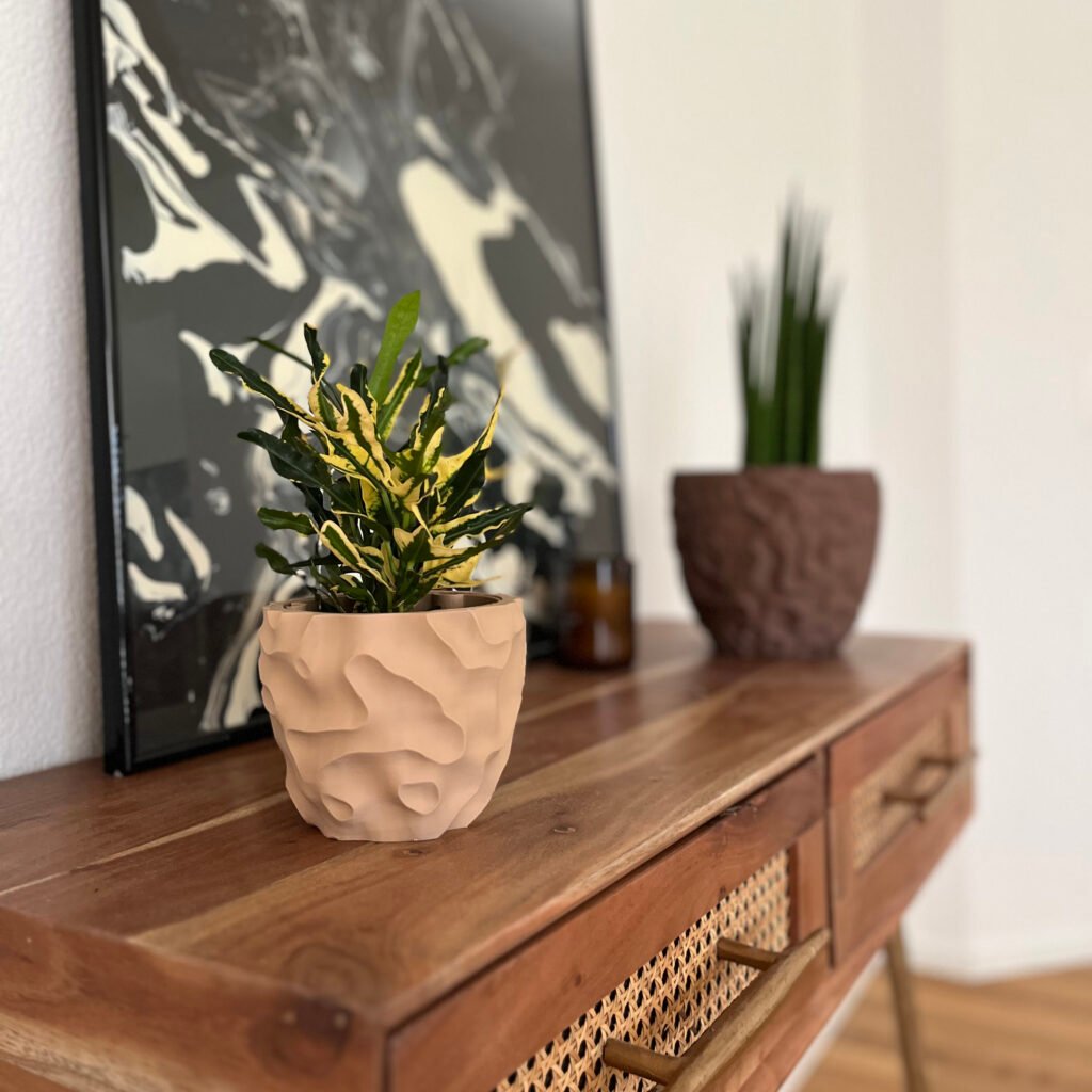 Modern beige 3D-printed planter with organic textures, placed on a wooden console