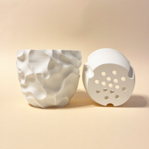 White 3D-printed planter with sculptural surface texture shown alongside its removable drainage insert