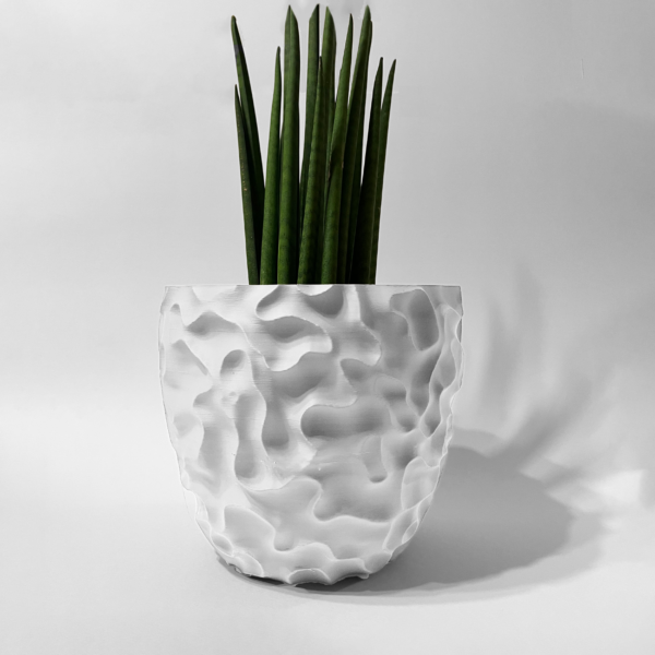 White 3D-printed sculptural planter with a textured surface, holding a tall snake plant