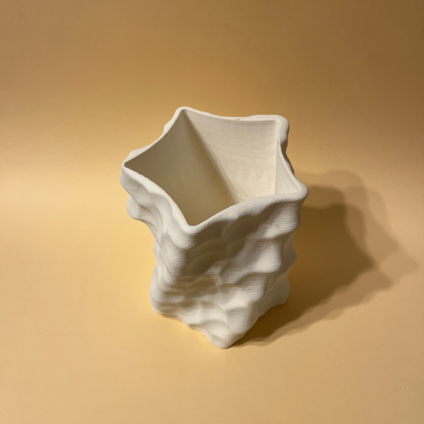 White 3D-printed sculptural Amphitrite vase with an organic, dimpled surface in peachy background