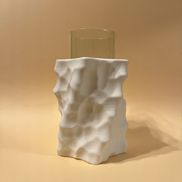 Tall glass vase partially encased in a white 3D-printed sculptural vase with a dimpled surface