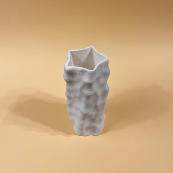 White 3D-printed sculptural vase with an organic, dimpled surface in peachy background
