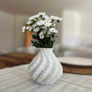 White 3D-printed sculptural vase with a wave-like surface, holding a bouquet of white daisies in modern interior