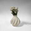 White 3D-printed sculptural vase with a wave-like surface, holding a bouquet of white daisies