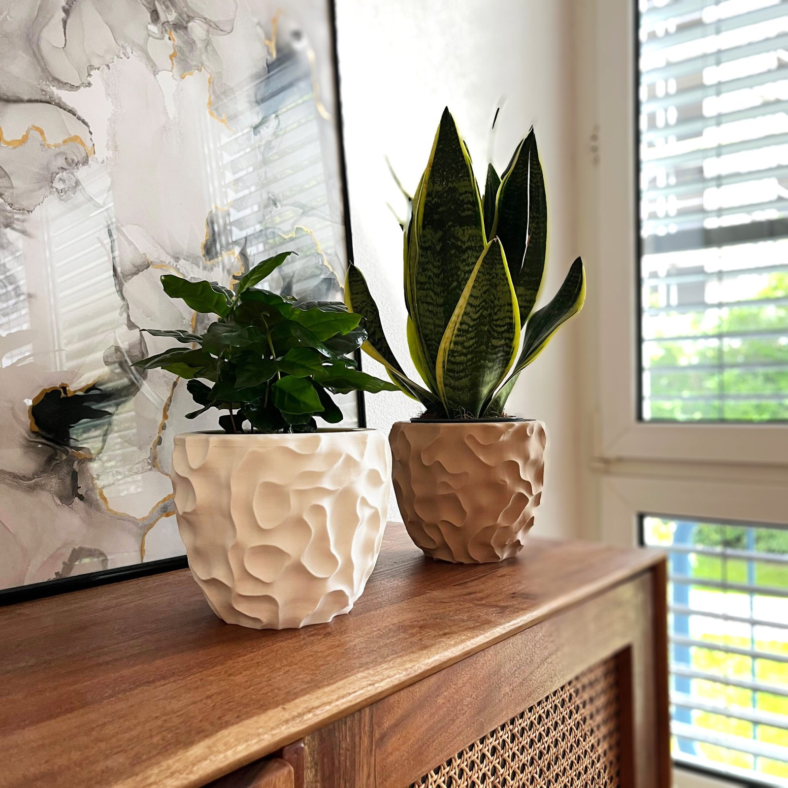 Two natural tones 3D-printed sculptural planters in brown and white, each filled with plants